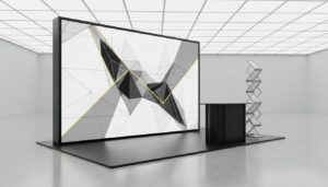 Large modular SEG light box display with geometric graphics at trade show booth with black counter and literature rack